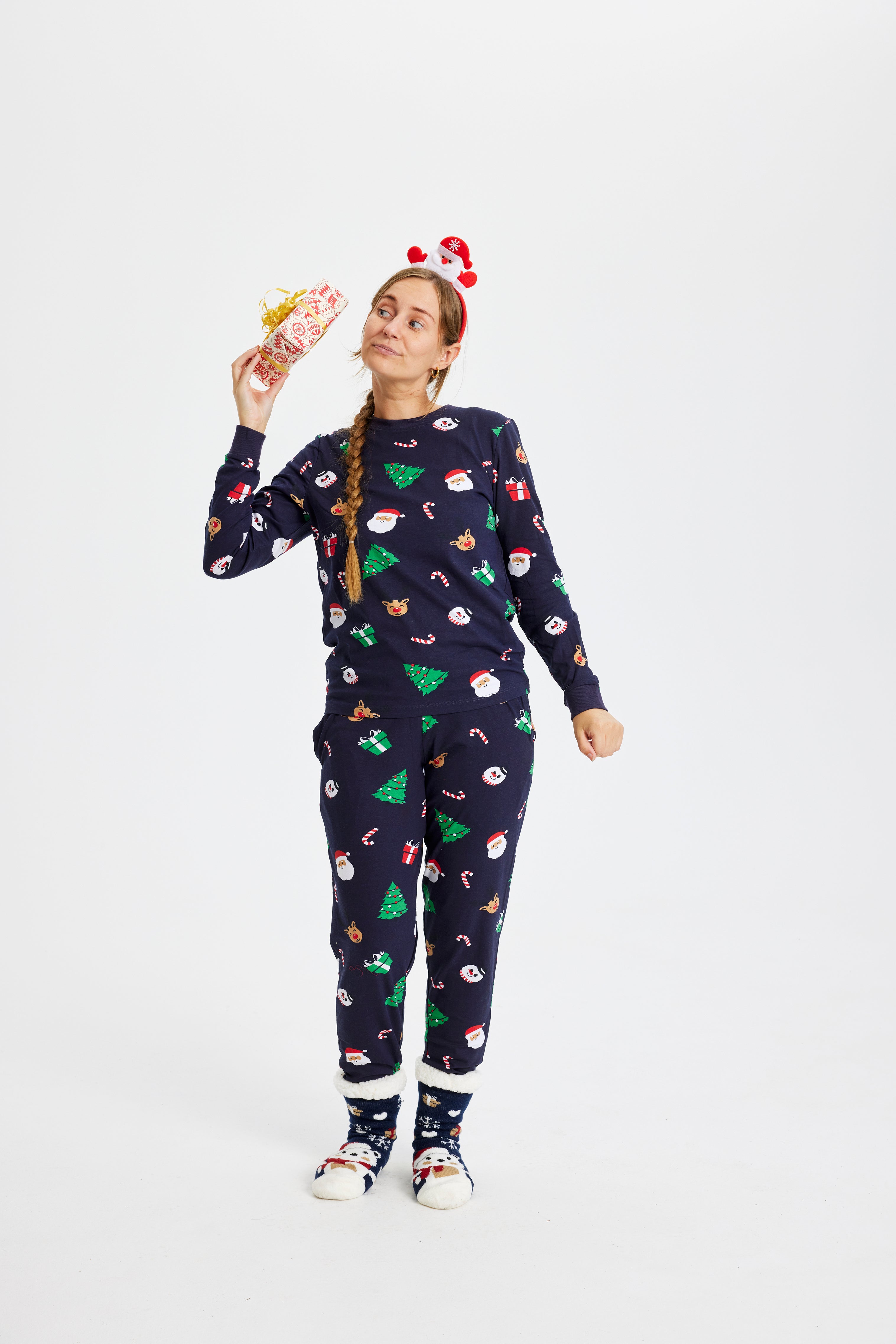 En kvinne i julepyjamas med en gave i hånden.